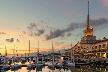 small sailboats in the seaport of Sochi against the backdrop of a sea station and a beautiful sunset - 581901215