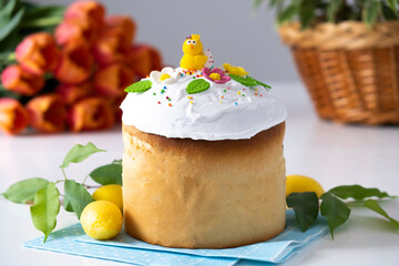 Traditional Ukrainian Easter cake with glace icing and spring decoration, orange tulips on background. Happy Easter in Christian traditions. Recipe of Easter bakery. Festive pastry for spring holidays