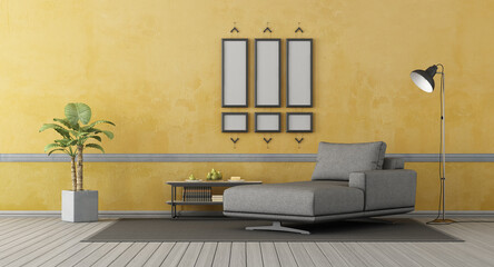Gray chaise lounge om old yellow wall