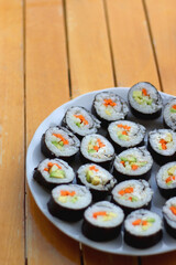 Plates with homemade sushi rolls on wooden table. Vegetarian cream cheese and vegetable sushi. Selective focus.