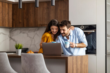 Couple in modern kitchen using laptop