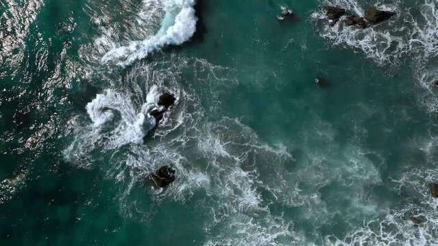 Tropical waves crashing on shore onto the beach. turqoise blue and sunny day aerial view of ocean waves 4k drone.