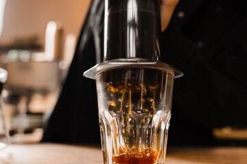 Aeropress coffee. Process of pouring coffee in cup. Barista is pushing aeropress for pouring coffee drops. Falling coffee drops in cup close-up.