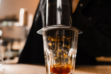 Aeropress coffee. Process of pouring coffee in cup. Barista is pushing aeropress for pouring coffee drops. Falling coffee drops in cup close-up.