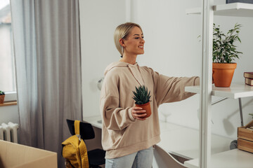 A young blond woman is arranging a shelf in her new room