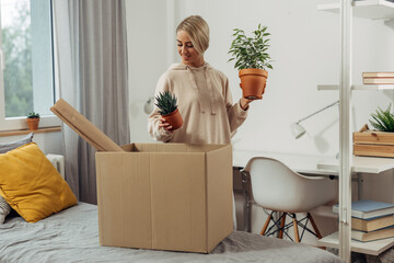 A young woman is piking up plants from the box