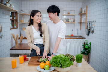 A couple of love cooking food together with smile of happiness, looking each other at kitchen.