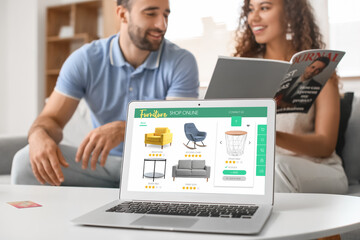 Young couple with laptop buying online new furniture at home