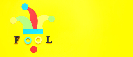 Paper hat and word FOOL on yellow background with space for text
