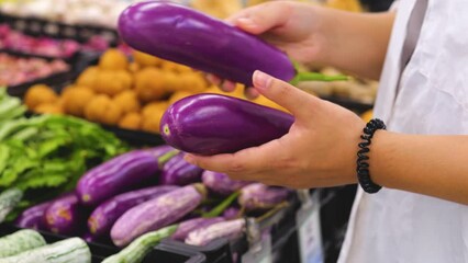 Young woman choosing eggplants in the supermarket. - Powered by Adobe