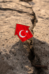 Earthquake in Turkey. The flag of Turkey in the form of a house standing on a broken slab with cracks. The idea of ​​a devastating earthquake in Turkey.