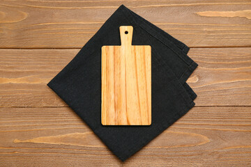 Folded napkin and cutting board on wooden background