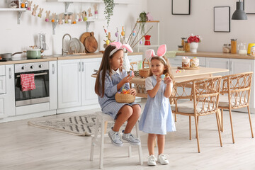 Cute little girls with Easter eggs in kitchen