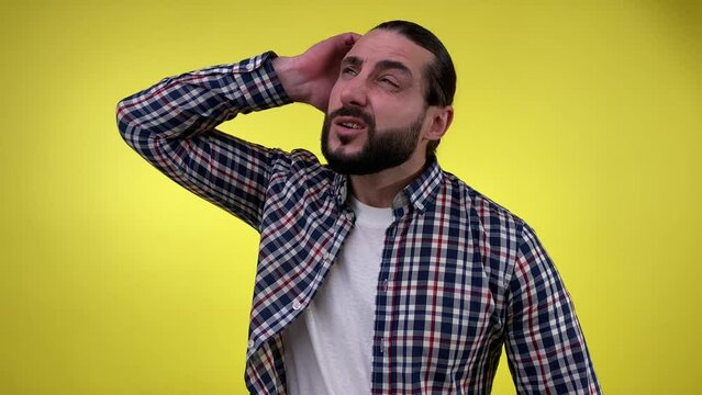 Portrait adult bearded man in casual clothing fail to remember, scratching head, thinking deeply, looking up isolated on yellow background. Facial expression, emotion, feeling, body sign concept