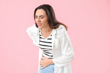 Young woman with appendicitis on pink background