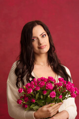 Beautiful brunette with a bouquet of pink roses