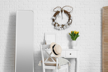 Interior of living room with Easter wreath, workplace and mirror