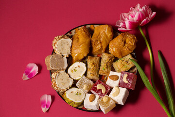 Still life of oriental sweets on a pink background with tulip