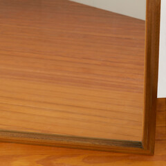 Full-Length Vintage walnut wood Floor Mirror. Vintage minimal beveled edge design. Close-up view of frame edge and wood flooring reflection. 