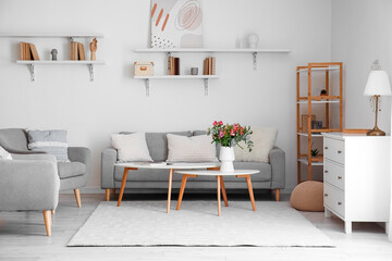 Stylish interior of light living room with flowers