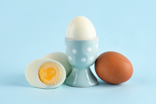 Holder with delicious boiled egg on blue background