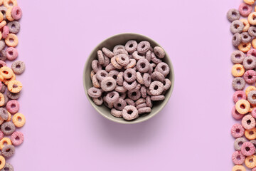 Bowl and heaps of colorful cereal rings on lilac background