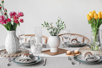 Beautiful table setting for International Women's Day celebration with flowers and burning candles in dining room