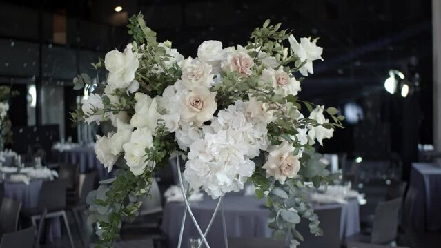 Flower arrangement on the wedding table. Wedding table decor in light colors. Floristic compositions of roses, hydrangea, eucalyptus on party banquet dining table. 