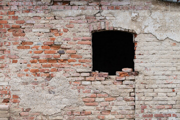 Background and texture of an old brick wall. A window is in the weathered wall that is missing the...