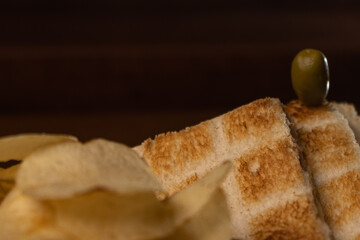 Fast food sandwich called toasted with an olive on top with french fries and orange juice.