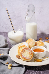 Plate with tasty cottage cheese pancakes, jam and milk on grunge background, closeup