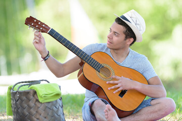 picture of young man adjusting guitar chords