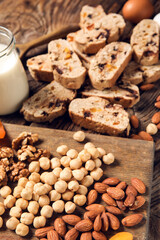 Delicious biscotti cookies and board with nuts on wooden background