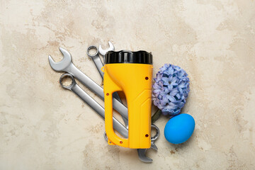 Wrenches with flashlight, Easter egg and hyacinth flower on grunge background