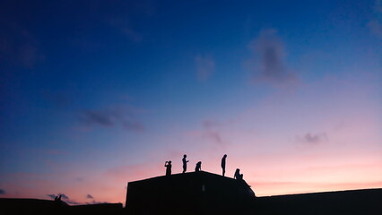 Cihou Fort, Qijin, Kaohsiung, Taiwan - August 8, 2017: people with silhouette standing on the top of a fort with sunset and blue and pink sky in the background