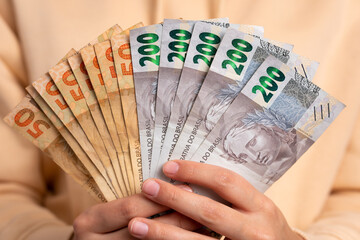 hands of brazilian woman showing money, brazilian Real in studio shot. finance, investment, offer, loan concept. 