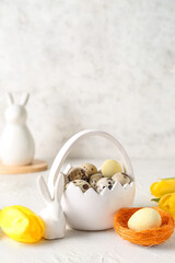 Basket with Easter quail eggs, bunny and tulip flowers on white background