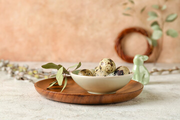 Bowl with Easter quail eggs and eucalyptus branch on white grunge background