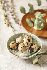 Bowl with Easter quail eggs and eucalyptus branch on white grunge background