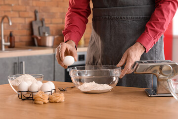 Man making dough for pasta at table in kitchen, closeup