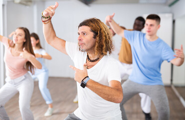 Adult positive man learning dance moves in dance hall