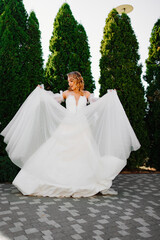 beautiful bride in a white delicate dress dances and spins in the park. 