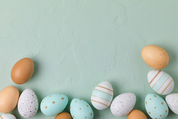Easter frame of pastel colored eggs on light green background. Flay lay, top view with copy space.