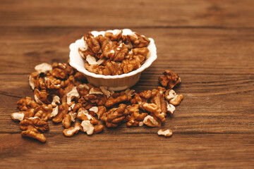 Dried walnut grains in a bowl on a wooden table.