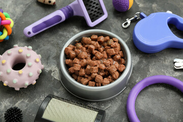 Composition with bowl of wet food and pet care accessories on grunge background