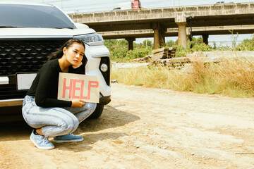 Asian woman with serious face sitting restlessly stressed in front of her car car running out of...