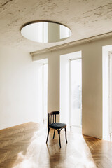 wooden vintage chair in a room dazzled by sunlight. chair in a studio with large windows and a round mirror on the ceiling.