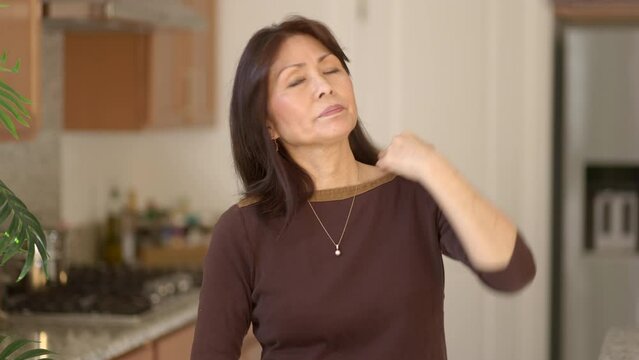 Attractive mature woman looking at camera brushing hair from face sitting at home