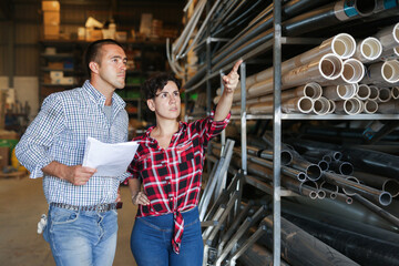 Manager and the hired worker conduct an inventory in the warehouse of building materials