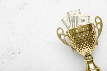 Gold cup with money on light background